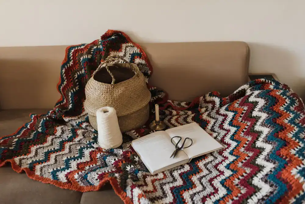 Cosy knitted blanket and pattern book on a wooden table